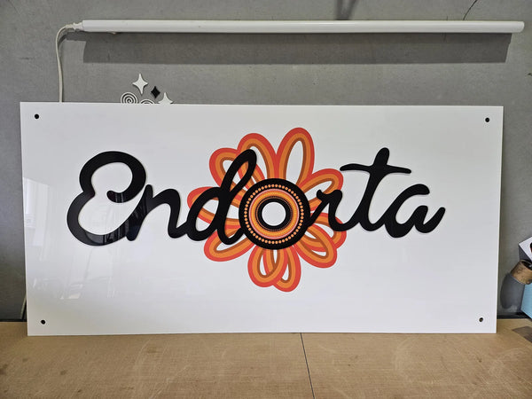 White acrylic Endorta sign with a bright orange flower logo