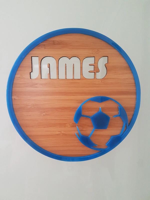 Round bamboo name plaque reading James with a blue-edged soccer ball