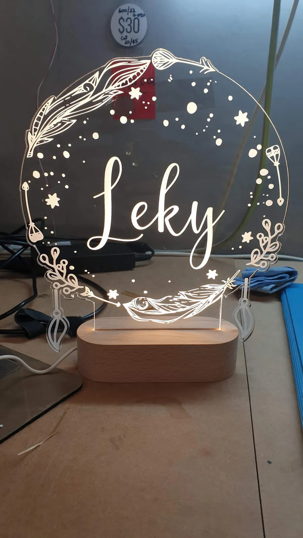 Engraved acrylic LED light with a floral wreath and the name Leky, on a wooden base