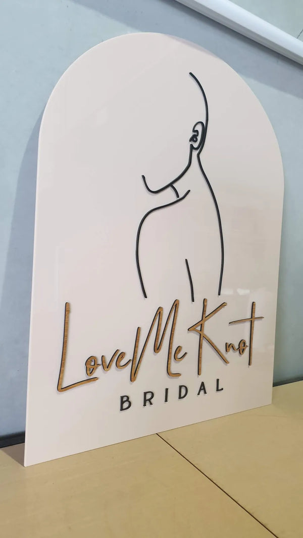 White arch-shaped Love Me Knot Bridal sign with a line-art figure