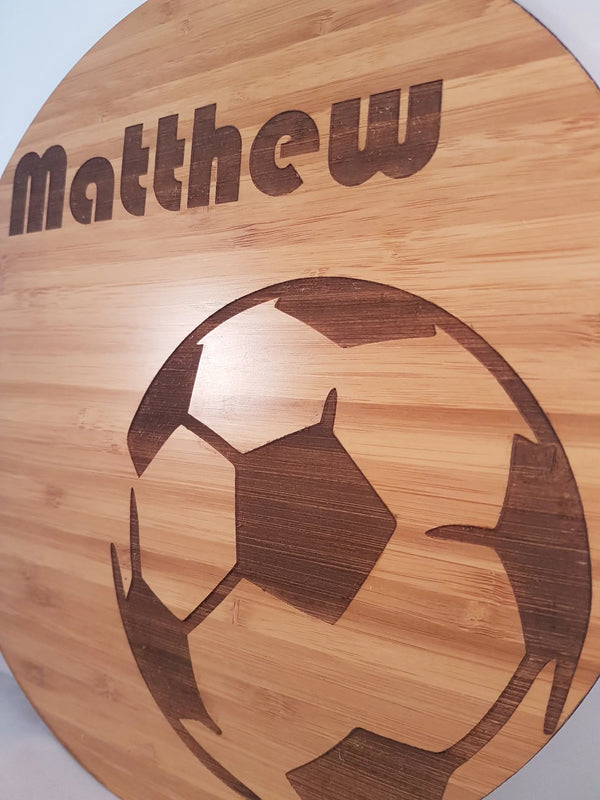 Close view of a round bamboo name plaque reading Matthew with an engraved soccer ball