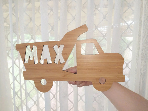 Cut-out bamboo tipper truck sign with the name Max, held in a hand