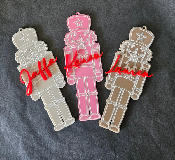 Three acrylic nutcracker ornaments with red script names