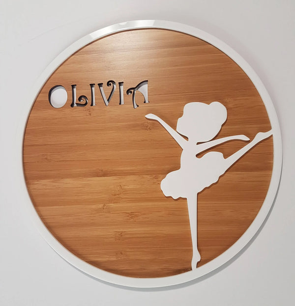 Round bamboo plaque reading Olivia with a white acrylic ballerina