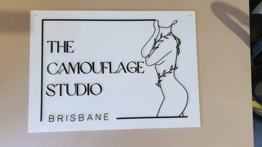 White acrylic The Camouflage Studio Brisbane sign with black line art