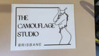 White acrylic The Camouflage Studio Brisbane sign with black line art
