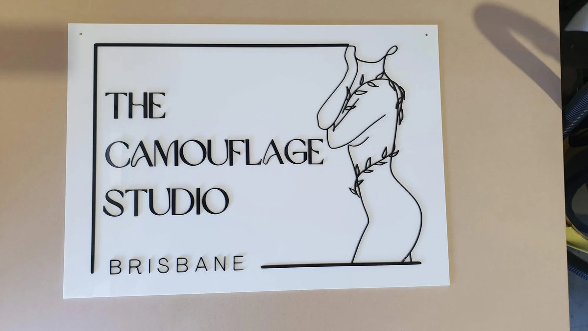 White acrylic The Camouflage Studio Brisbane sign with black line art