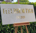 White rectangular FLEURBEAUTYCO Est 2020 sign with gold mirror lettering on a timber easel