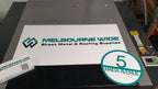 White Melbourne Wide Sheet Metal and Roofing Supplies sign on the laser cutter with a house number disc