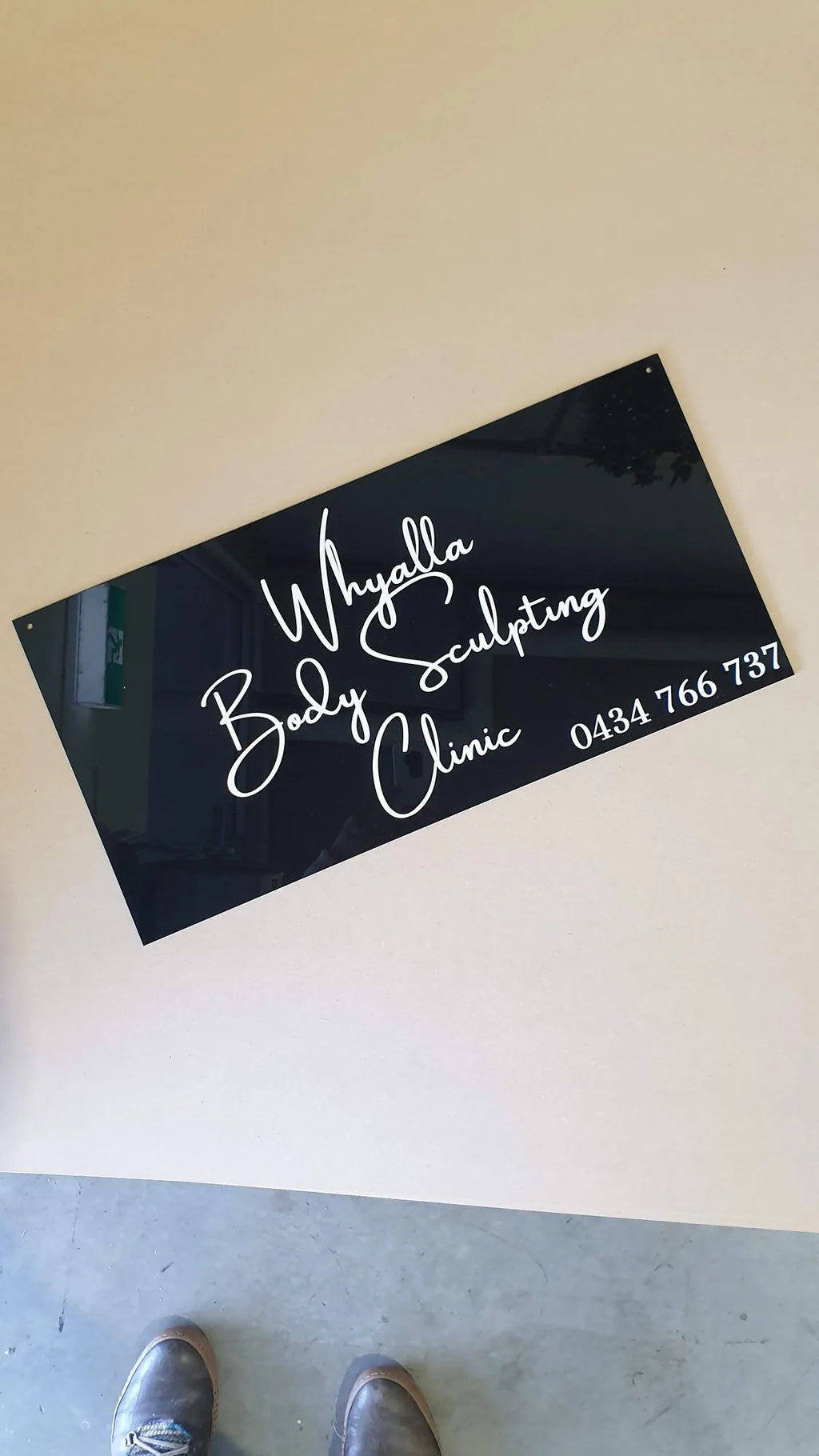Black acrylic Whyalla Body Sculpting Clinic sign with white script and phone number