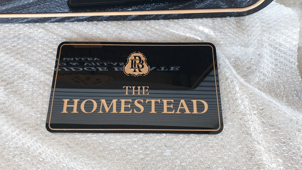 Black acrylic The Homestead sign with gold crest and lettering
