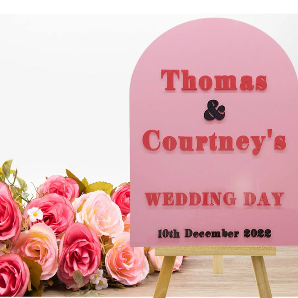 Pink arch acrylic wedding sign reading Thomas and Courtney's wedding day, 10th December 2022